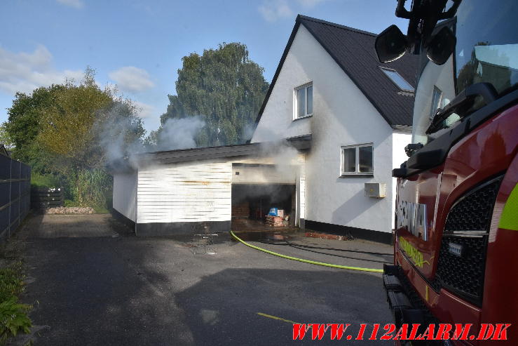 Ild i Carport. Nørre Bygade i Grejs. 02/08-2024. Kl. 17:34.